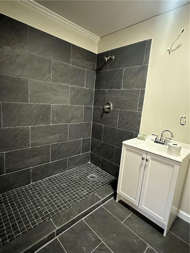 bathroom featuring a tile shower, vanity, tile patterned floors, and ornamental molding