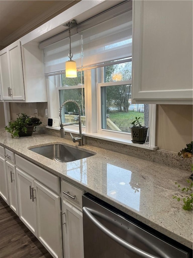 kitchen with stainless steel dishwasher, light stone counters, sink, white cabinetry, and hanging light fixtures