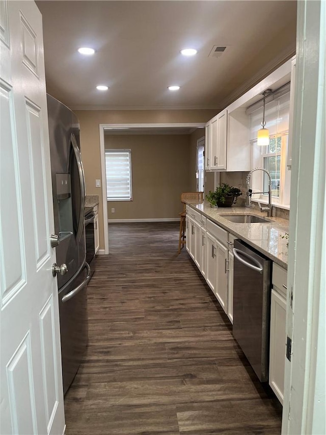 kitchen featuring light stone countertops, sink, pendant lighting, white cabinets, and appliances with stainless steel finishes