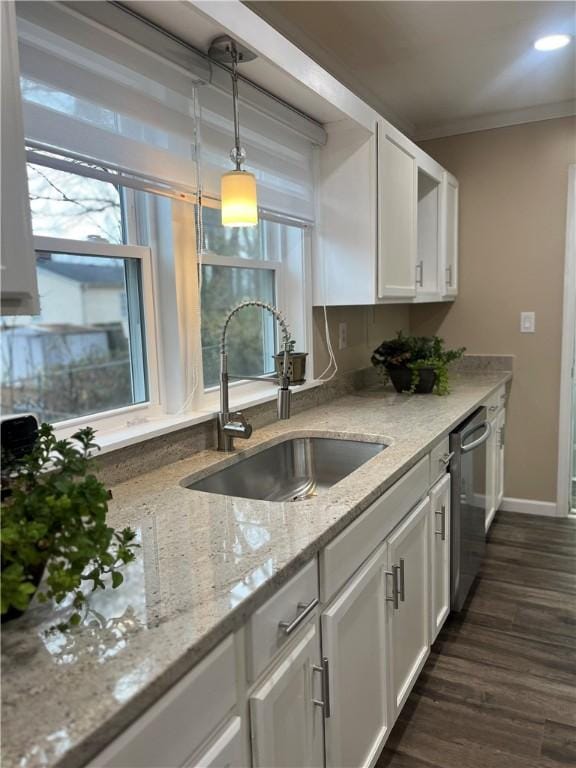 kitchen featuring light stone counters, stainless steel dishwasher, sink, white cabinets, and hanging light fixtures