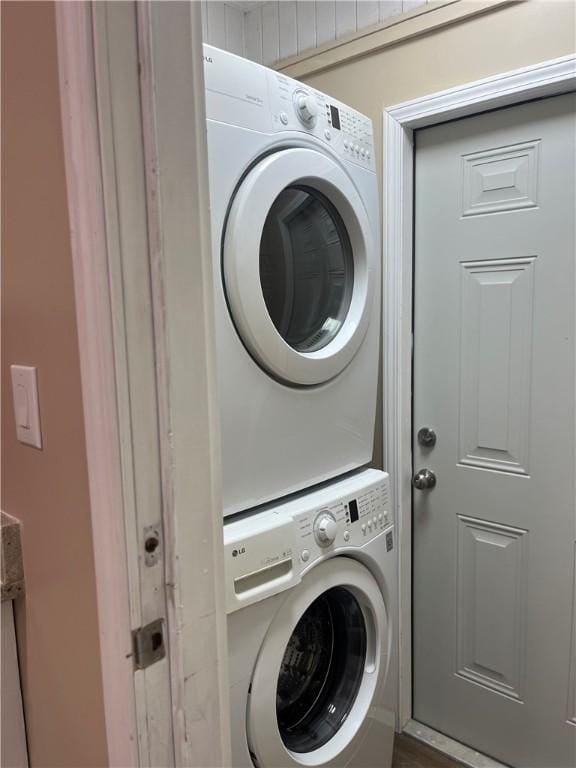 laundry area with stacked washer / dryer and hardwood / wood-style floors