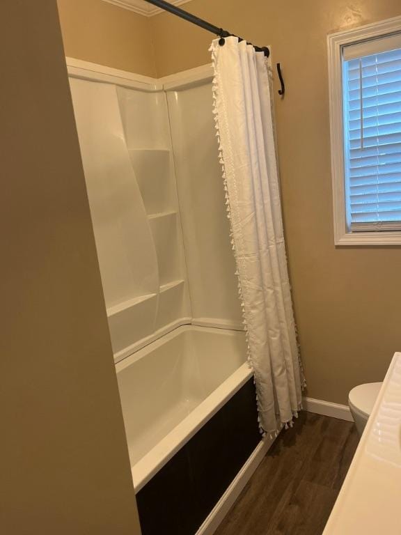 bathroom with hardwood / wood-style floors, toilet, and shower / tub combo