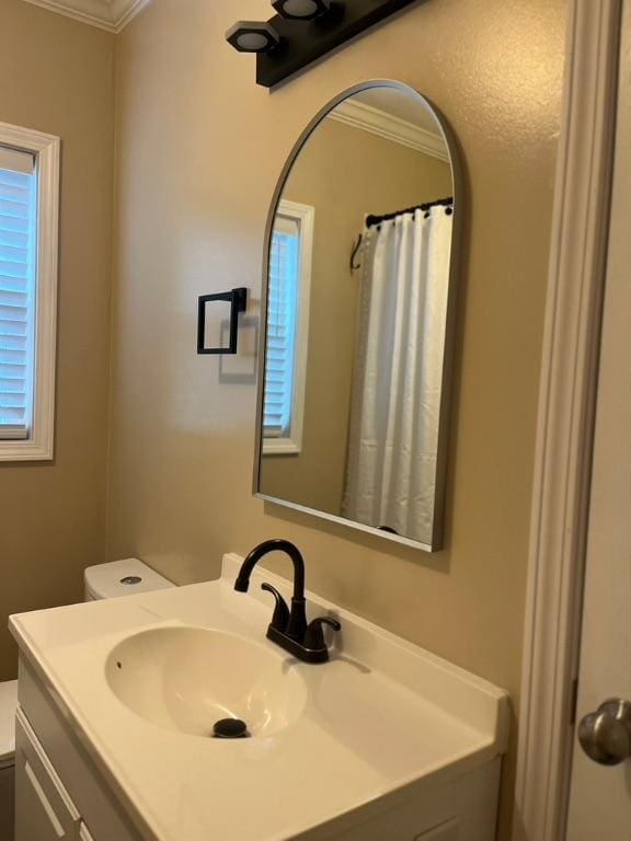 bathroom with vanity, toilet, and crown molding