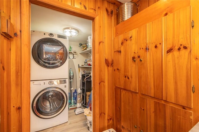 laundry area with stacked washer and dryer and light wood-type flooring