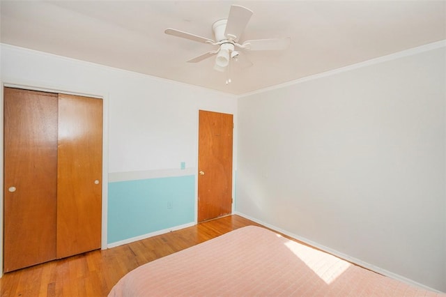 unfurnished bedroom with hardwood / wood-style floors, a closet, ceiling fan, and ornamental molding