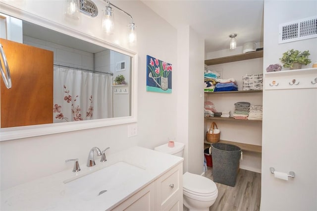 bathroom featuring curtained shower, vanity, wood-type flooring, and toilet