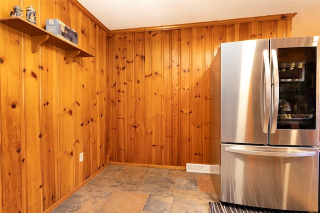 kitchen featuring wooden walls and stainless steel refrigerator