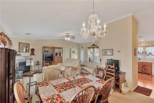 carpeted dining area with ceiling fan with notable chandelier, a fireplace, and vaulted ceiling