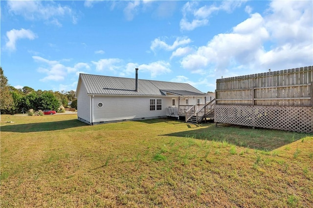 rear view of house featuring a wooden deck and a yard