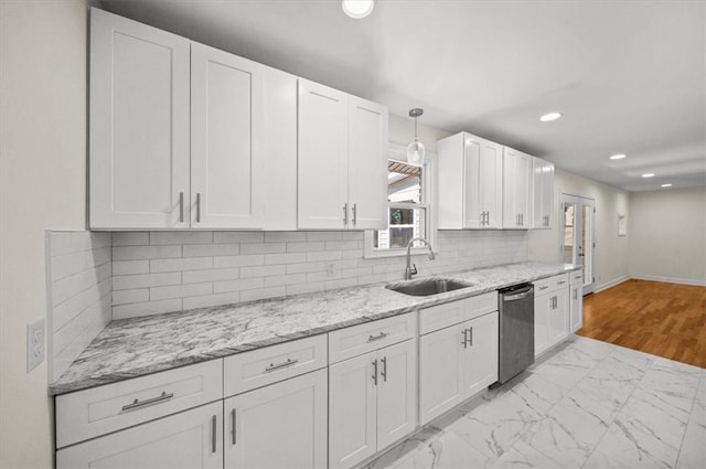 kitchen featuring pendant lighting, dishwasher, sink, light stone countertops, and white cabinetry