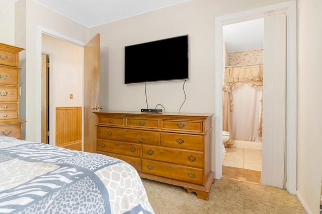 bedroom featuring connected bathroom and light colored carpet