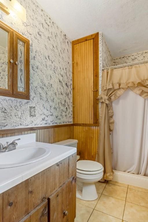 bathroom featuring walk in shower, tile patterned floors, toilet, wooden walls, and vanity