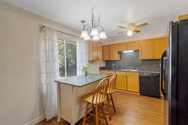 kitchen with black appliances, decorative backsplash, decorative light fixtures, light hardwood / wood-style floors, and a kitchen bar