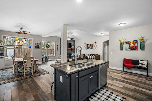 kitchen featuring dishwasher, sink, dark hardwood / wood-style floors, pendant lighting, and a center island with sink