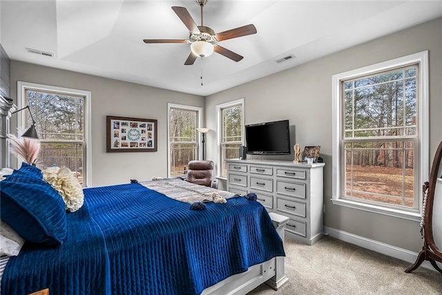 bedroom featuring ceiling fan, light carpet, and multiple windows