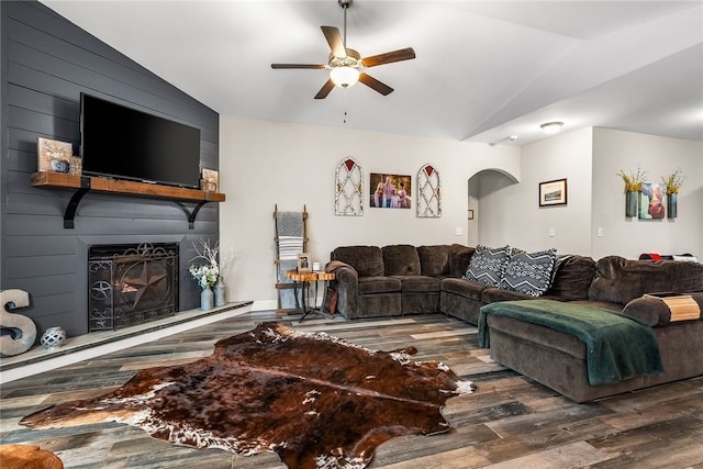 living room featuring ceiling fan, dark hardwood / wood-style flooring, lofted ceiling, and a fireplace