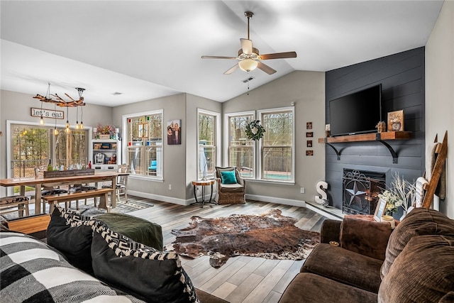 living room featuring ceiling fan, a large fireplace, wood-type flooring, and lofted ceiling