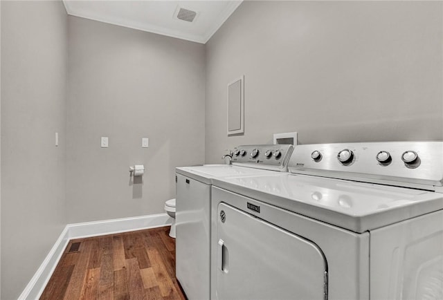 washroom with washing machine and clothes dryer, crown molding, and wood-type flooring