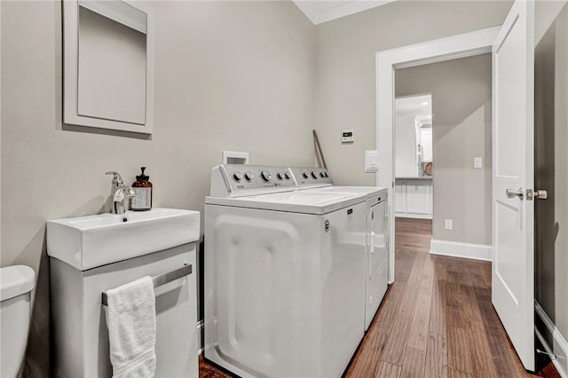 laundry room with hardwood / wood-style floors, separate washer and dryer, crown molding, and sink