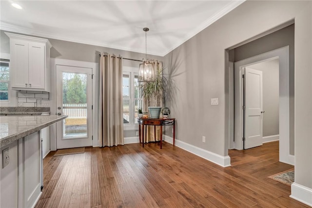 unfurnished dining area featuring crown molding, dark hardwood / wood-style flooring, and a chandelier