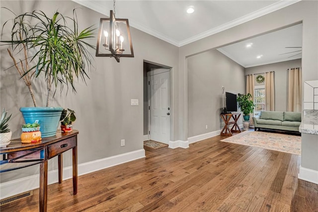 foyer featuring hardwood / wood-style floors, a notable chandelier, and crown molding