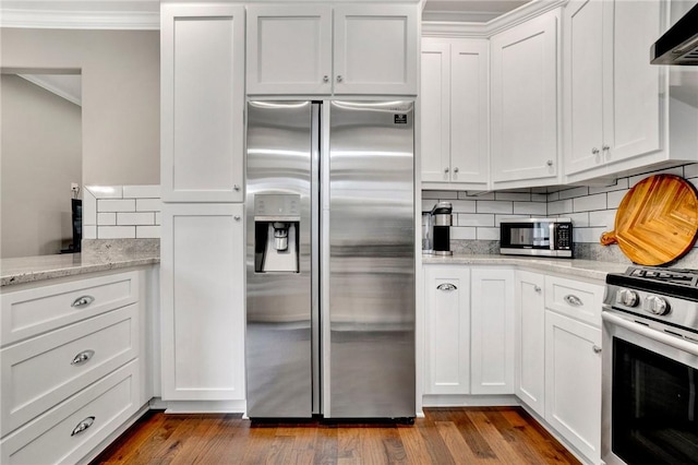 kitchen featuring light stone countertops, wall chimney exhaust hood, stainless steel appliances, crown molding, and white cabinets