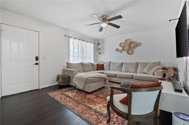 living room with ceiling fan, dark wood-type flooring, a textured ceiling, and ornamental molding