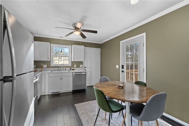 dining space featuring ceiling fan, sink, dark wood-type flooring, a textured ceiling, and ornamental molding