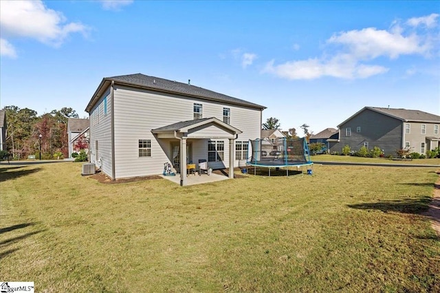 back of property with cooling unit, a patio area, a trampoline, and a yard