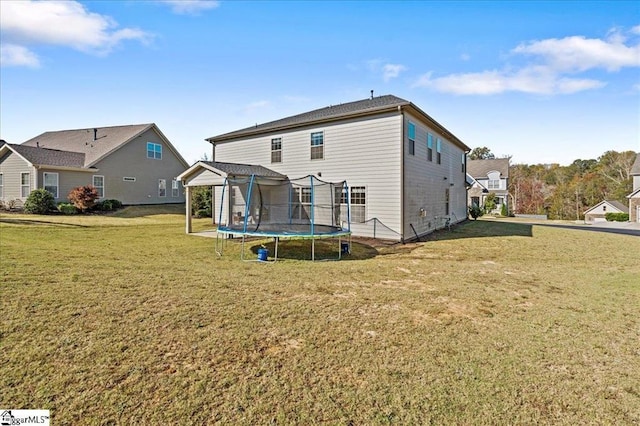 back of house with a trampoline and a yard