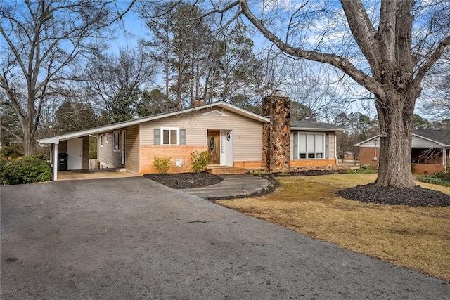 ranch-style house featuring a front lawn and a carport