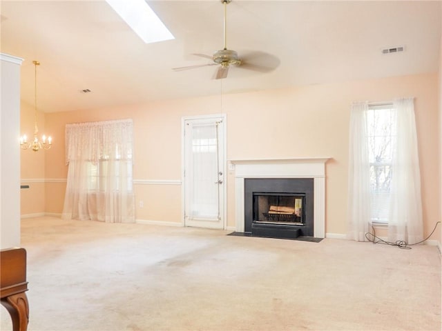 unfurnished living room featuring carpet flooring, ceiling fan with notable chandelier, and lofted ceiling with skylight