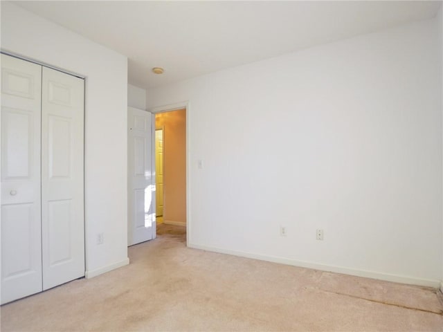 unfurnished bedroom featuring a closet and light colored carpet