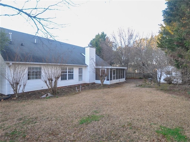 rear view of property with a lawn and a sunroom