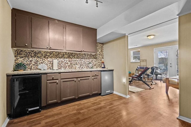 bar featuring fridge, light hardwood / wood-style flooring, dark brown cabinets, and wine cooler