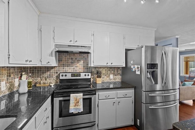 kitchen featuring appliances with stainless steel finishes, dark stone counters, crown molding, and white cabinetry