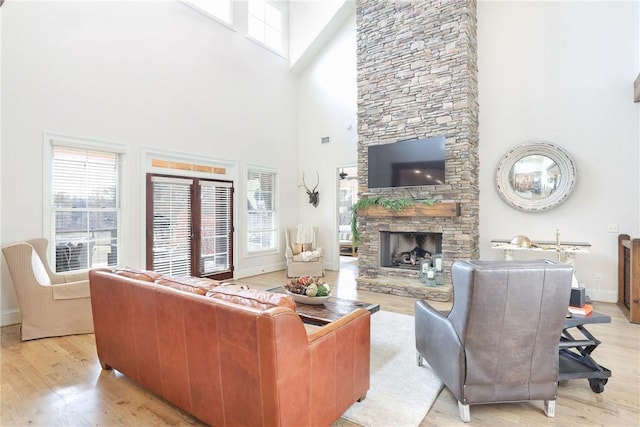 living room with a towering ceiling, a fireplace, and light hardwood / wood-style flooring