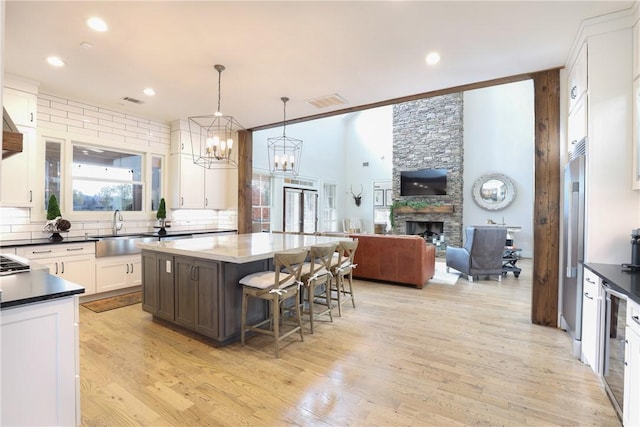 kitchen featuring a breakfast bar, a center island, sink, pendant lighting, and a fireplace