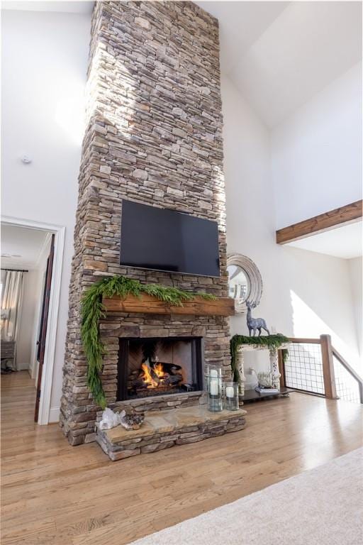 living room with wood-type flooring, a fireplace, and high vaulted ceiling