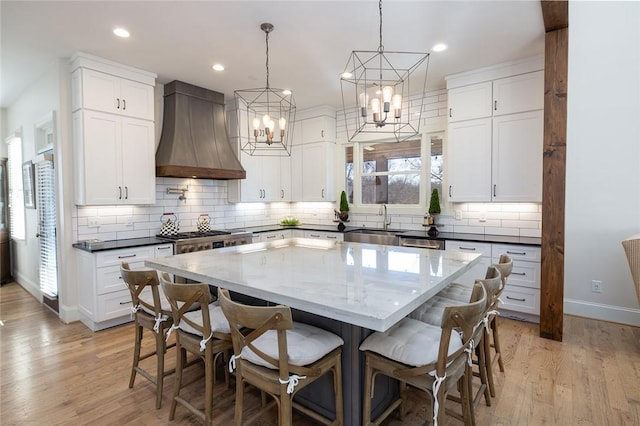 kitchen featuring a center island, white cabinets, custom range hood, and light hardwood / wood-style flooring