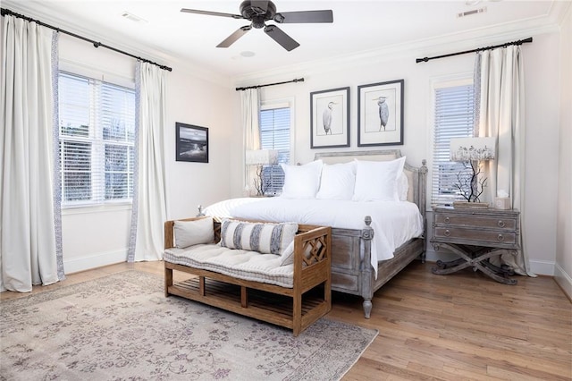 bedroom featuring multiple windows, ceiling fan, ornamental molding, and light wood-type flooring