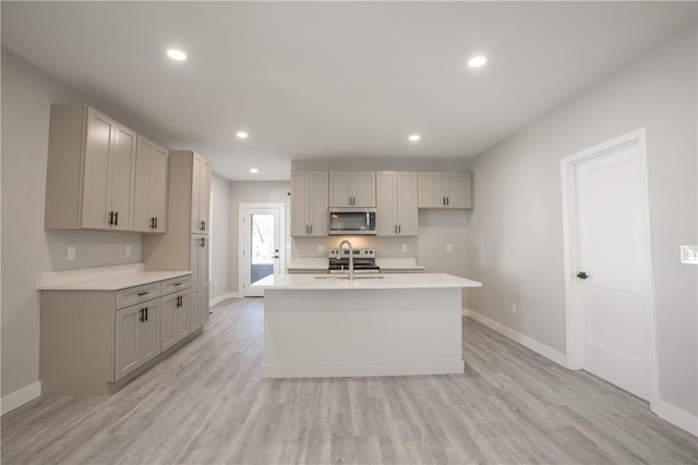 kitchen with gray cabinets, stainless steel appliances, and light hardwood / wood-style floors