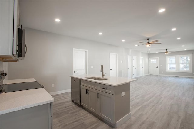 kitchen featuring gray cabinetry, ceiling fan, dishwasher, sink, and a center island with sink