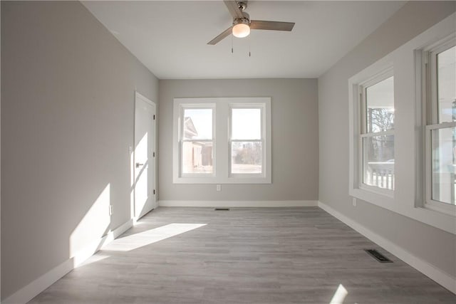 empty room with ceiling fan and light hardwood / wood-style flooring