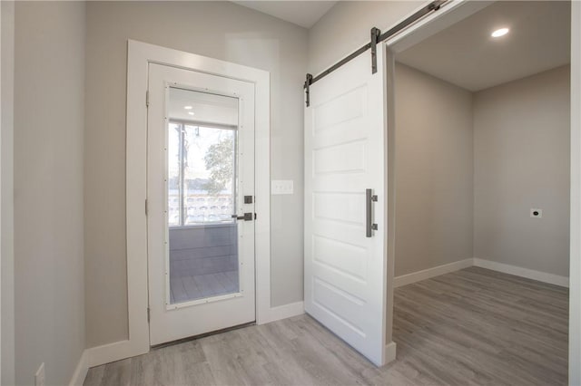 doorway to outside with a barn door and light wood-type flooring