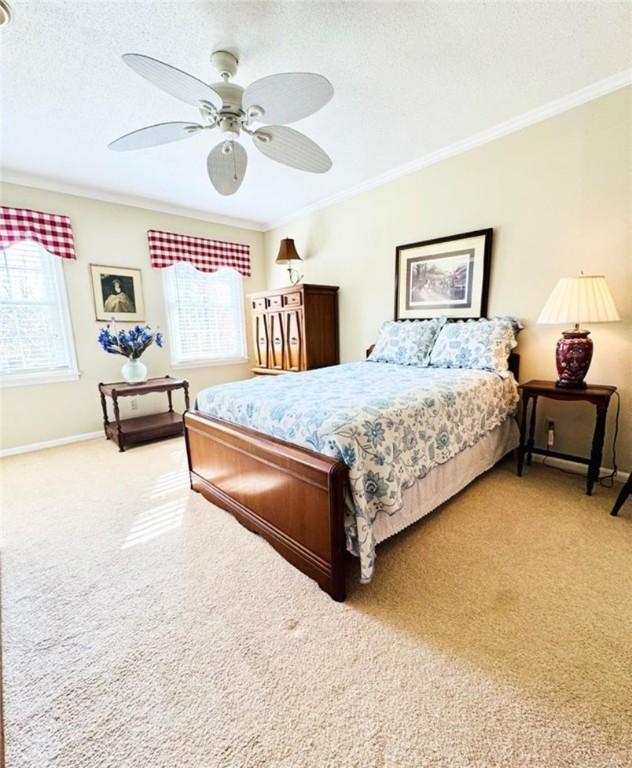 bedroom with light carpet, ceiling fan, and crown molding