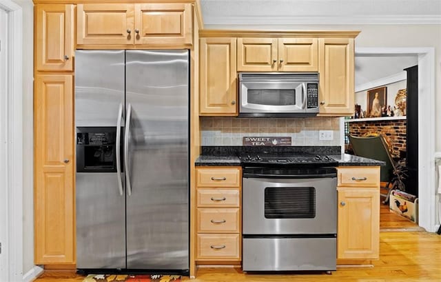 kitchen featuring decorative backsplash, ornamental molding, dark stone counters, stainless steel appliances, and light brown cabinets