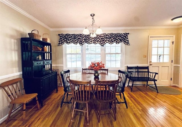 dining area with hardwood / wood-style floors, a healthy amount of sunlight, a textured ceiling, and ornamental molding