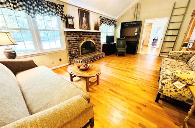 living room with crown molding, a fireplace, wood-type flooring, and vaulted ceiling