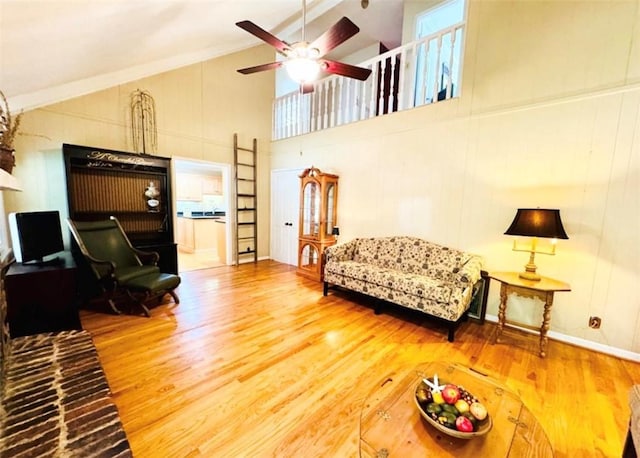 living room featuring ceiling fan, a healthy amount of sunlight, wood-type flooring, and high vaulted ceiling